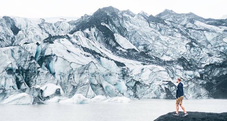 Persona parada frente a un glaciar.