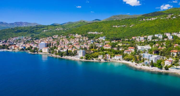 Vue côtière d'une ville avec des collines et une eau bleue claire.
