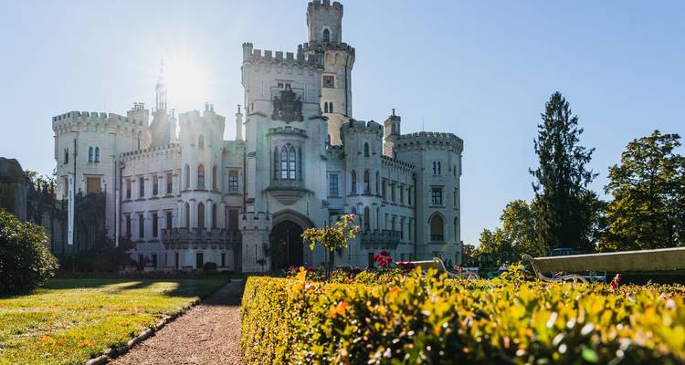 Castillo con luz solar y jardines en primer plano.