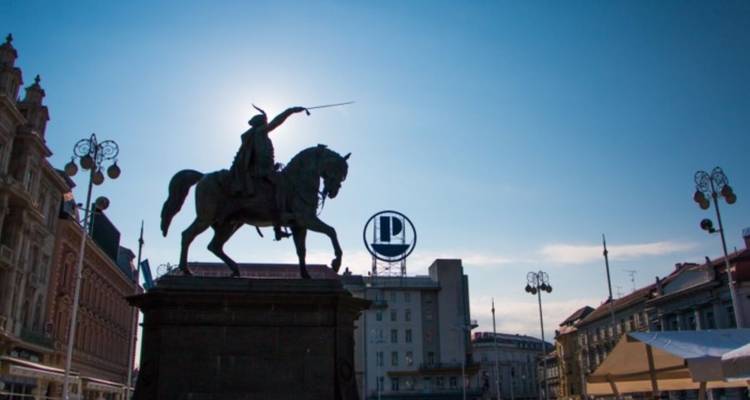 Silhouette de statue équestre avec des bâtiments en arrière-plan.