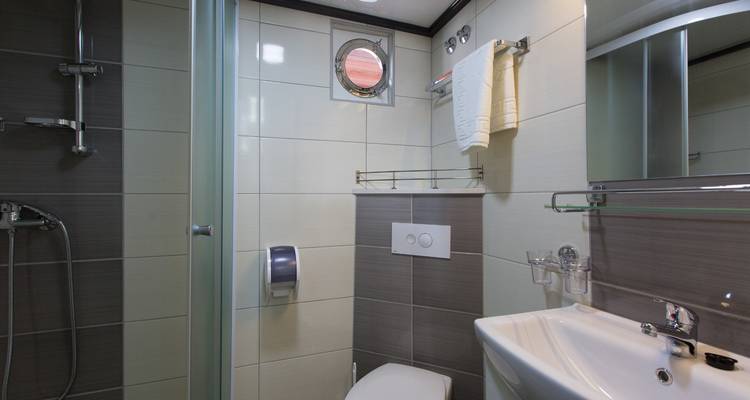 An interior of a bathroom with modern fixtures and a small porthole.