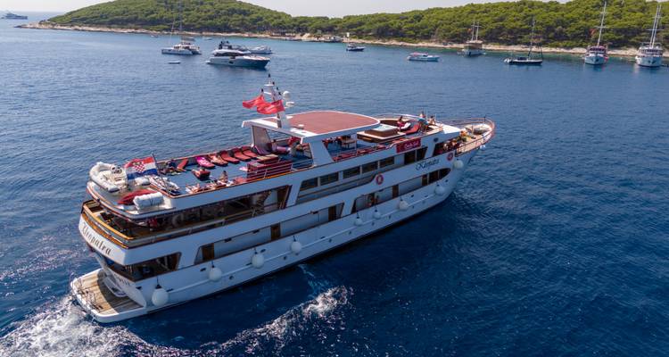 Un crucero navegando en aguas azules cristalinas con varios yates cerca.