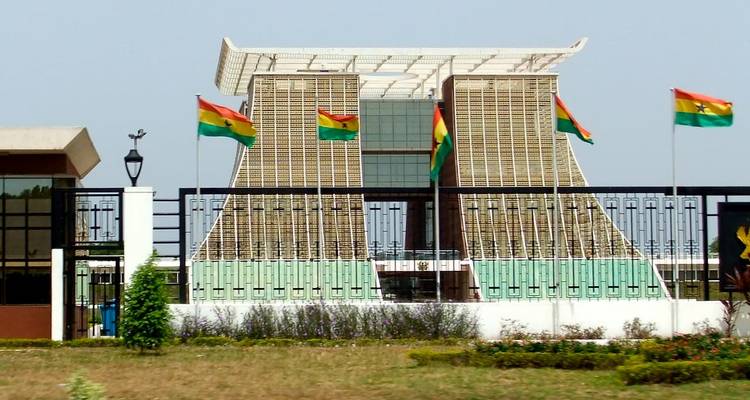 Un edificio moderno con banderas ghanesas ondeando en la parte superior.