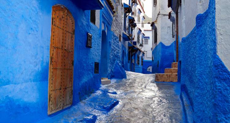 Een smalle straat met blauw geverfde gebouwen, waarschijnlijk in Chefchaouen.