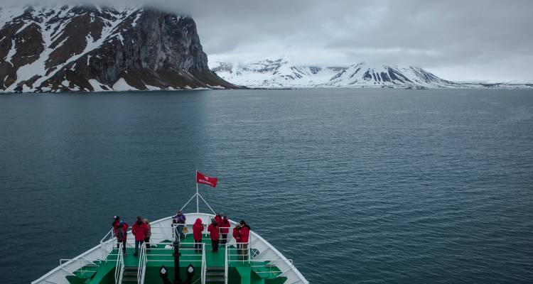Des personnes sur un navire près de paysages montagneux glacés.