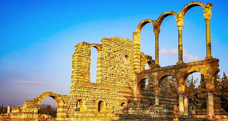 Ruines pittoresques avec arches contre un ciel de coucher de soleil.