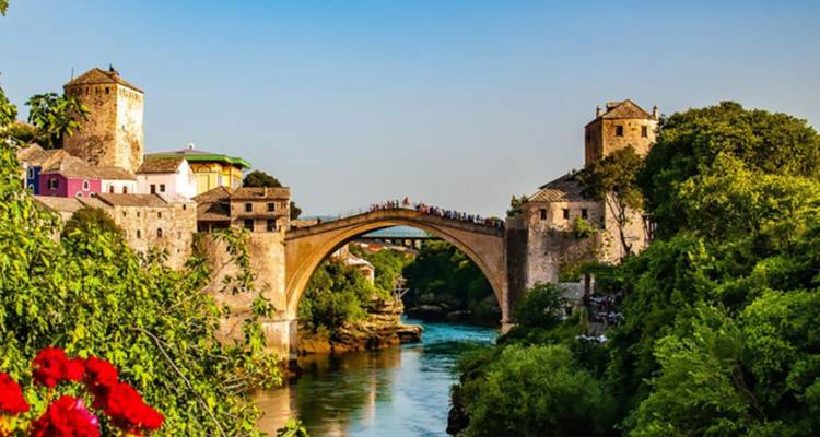 Famoso puente que se arquea sobre un río con colinas y casas.