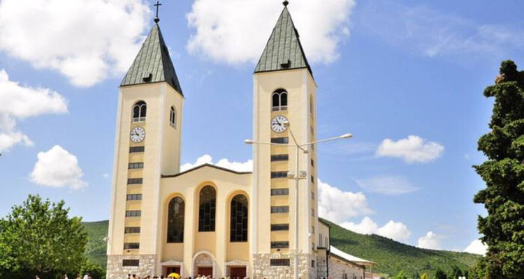 Iglesia de dos torres con gente reunida afuera.