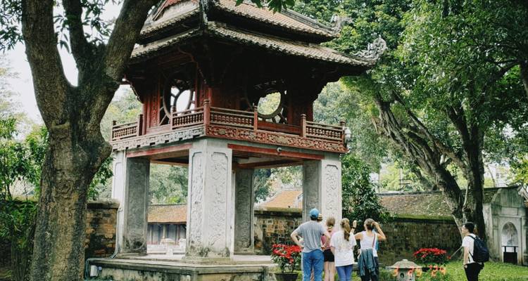 Reisegruppe hört vor dem roten Pavillon im Tempel der Literatur in Hanoi zu.