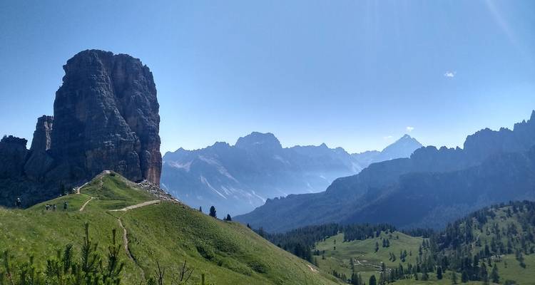 Una montaña grande en un paisaje de hierba con cielo azul.