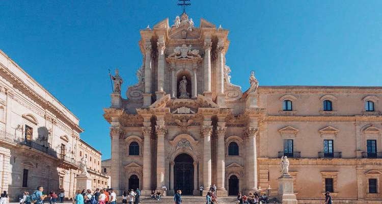 Catedral barroca con turistas en una plaza.