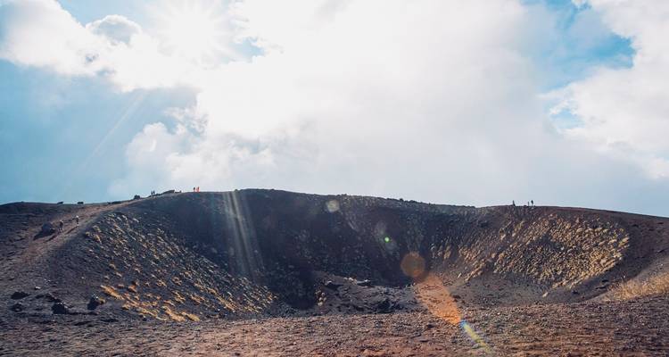 Cráter volcánico con luz solar atravesando las nubes.