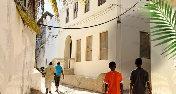 Rue étroite avec des gens qui marchent le long de maisons colorées.