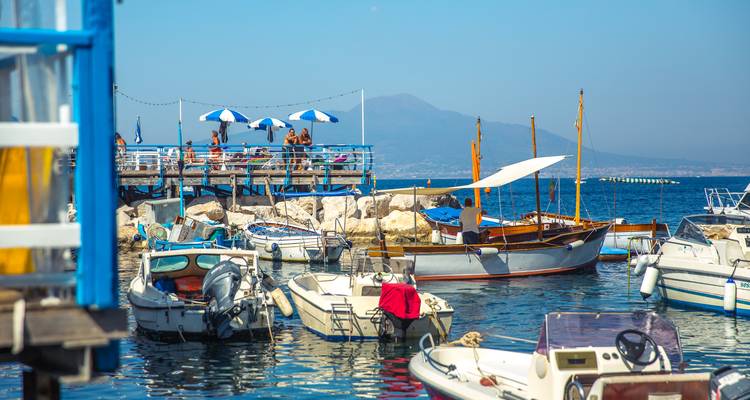 Boats docked at a harbor with a mountain view.