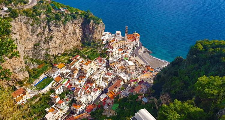Bird's-eye view of colourful coastal village Atrani perched between cliff walls and blue sea.