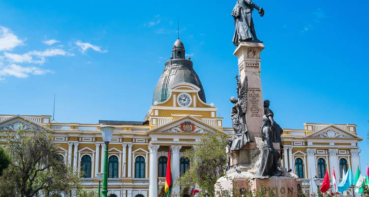 Statuentragenes Denkmal steht vor dem gelben und weißen neoklassizistischen Regierungspalast in La Paz.