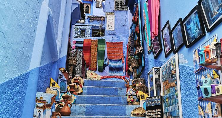 Verschillende textielwaren hangend aan blauw geschilderde trappen met levendige kleuren.