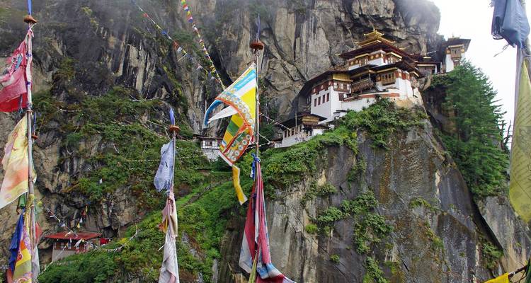 Monastère du Nid du Tigre perché sur une falaise avec des drapeaux de prière