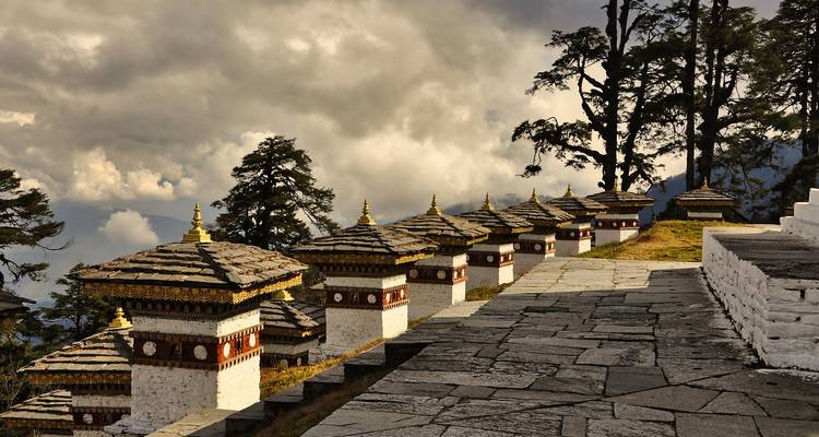 Une rangée de stupas aux sommets dorés se détachant sur un ciel dramatique