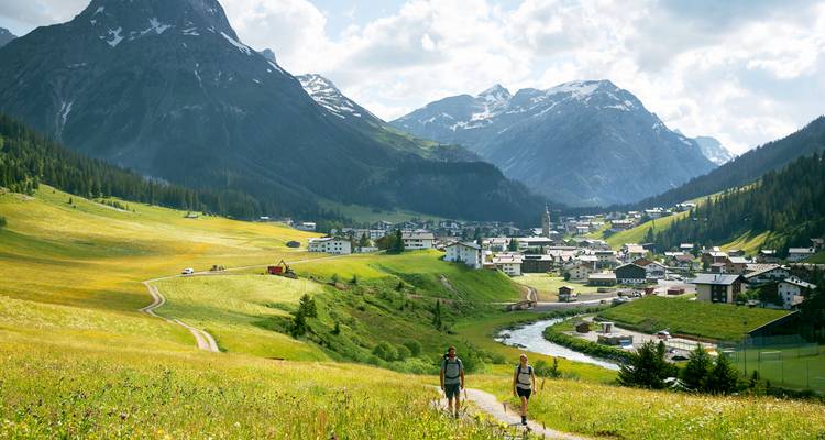 Wanderer, die auf einem Weg durch ein üppiges Tal mit Bergen in Lech gehen.