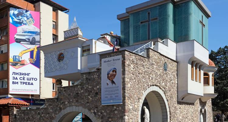 Un bâtiment moderne avec des banderoles et une statue de Mère Teresa.