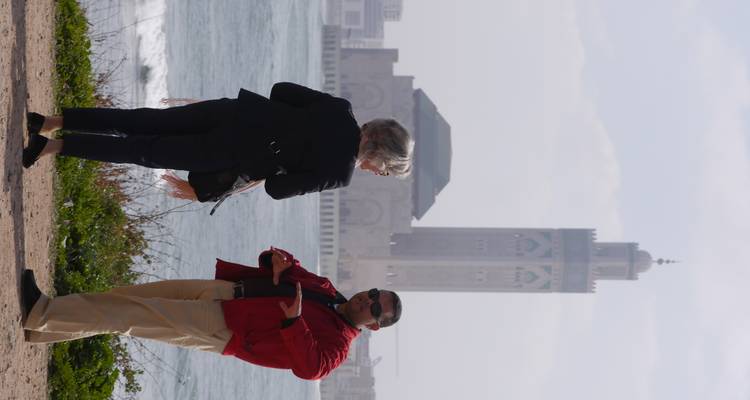 Deux personnes debout près de l'océan avec une mosquée en arrière-plan.