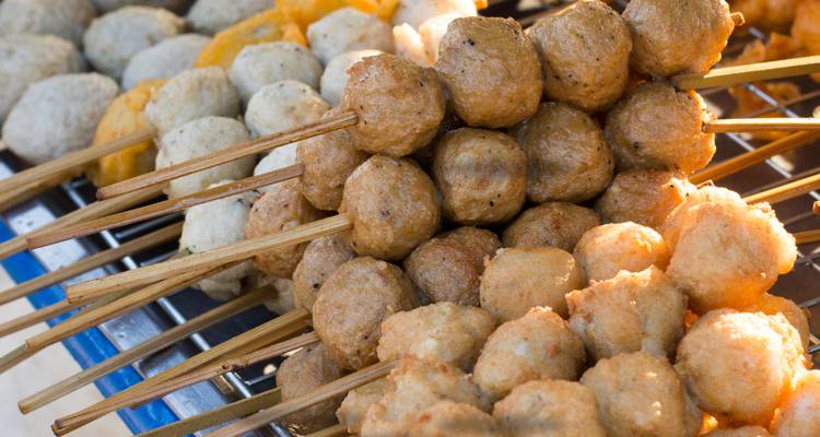 Brochettes de diverses boulettes de viande grillées en vitrine.