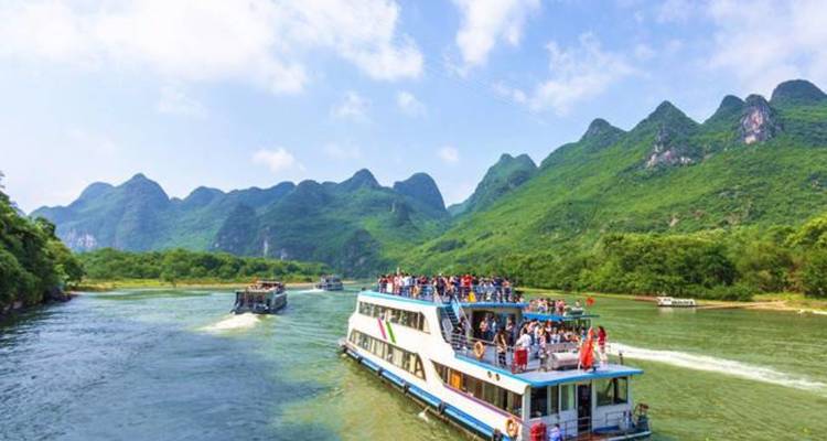 Bateaux touristiques naviguant sur une rivière avec des montagnes karstiques.