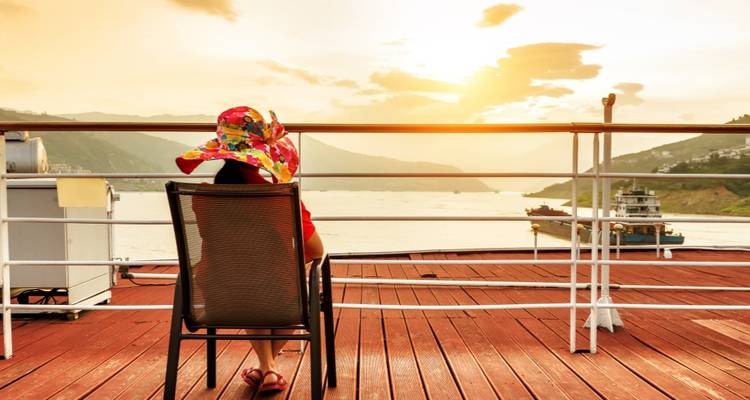 Une personne se détendant sur un bateau de croisière au coucher du soleil, observant la rivière.