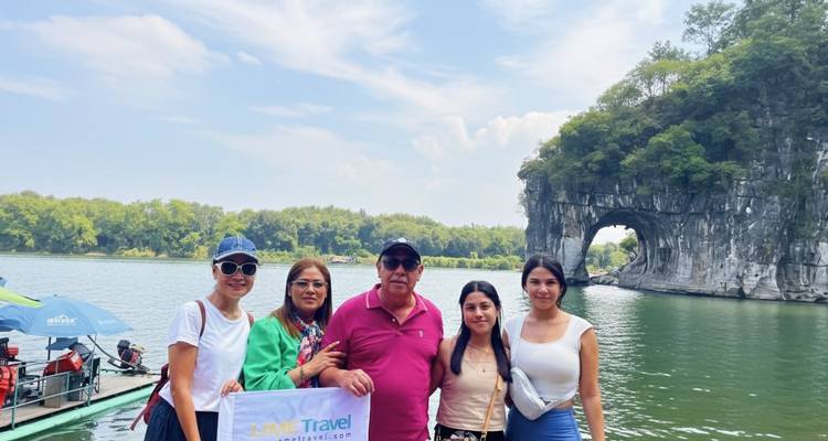 Gruppe von Touristen, die mit einem natürlichen Steinbogen und Wasser posiert.