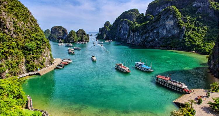 Impresionante vista aérea de la Bahía de Halong con barcos en agua turquesa entre islotes de piedra caliza.