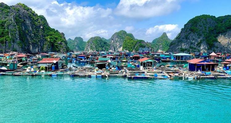 Pueblo flotante colorido en una bahía rodeado de islas de piedra caliza.