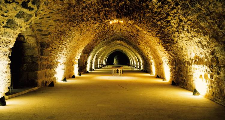 Dramatisch beleuchteter Steintunnel mit sich wiederholenden Bögen, die eine goldene Perspektive schaffen