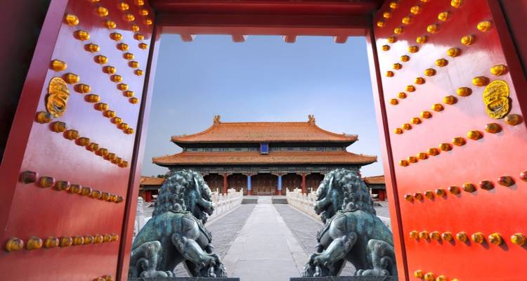 Zicht op een historisch Chinees paleis door een grote sierlijke poort met leeuwenbeelden.