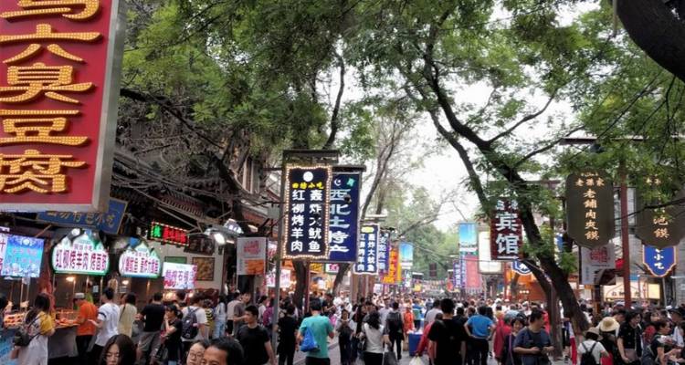 Drukke straatmarkt met veel mensen en kleurrijke borden.