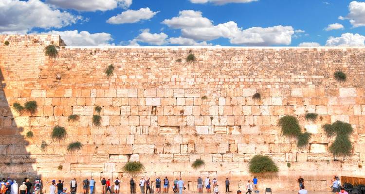 Des gens priant devant un grand mur ancien