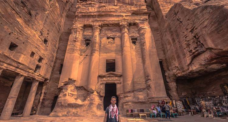 Des gens et des chameaux devant un monument taillé dans la roche