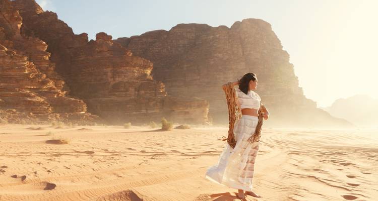 Femme en robe blanche marchant dans le désert