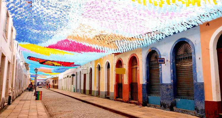 Kleurrijke straat versierd met hangende papieren banieren in een koloniale stad.