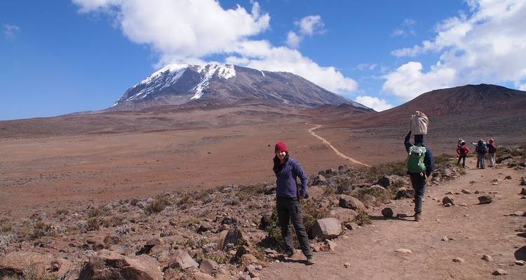 Excursionistas caminando hacia el Monte Kilimanjaro por un sendero.