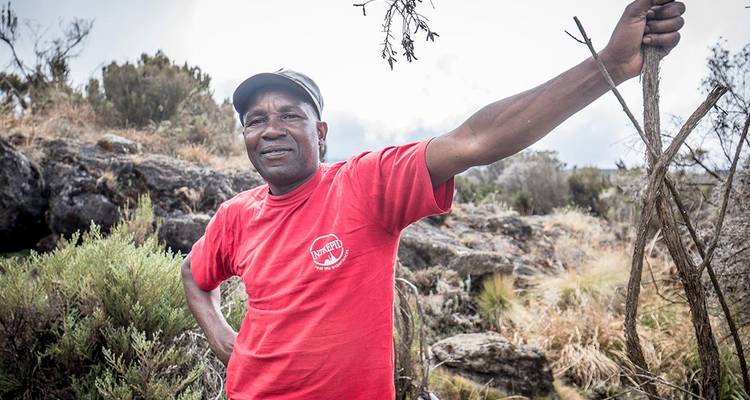 Guía local posando al aire libre con vegetación alrededor.