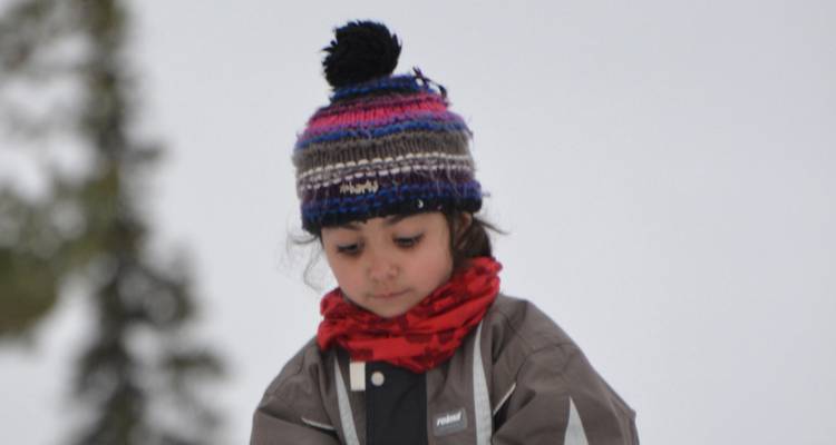 Enfant en vêtements d'hiver debout dans la neige.