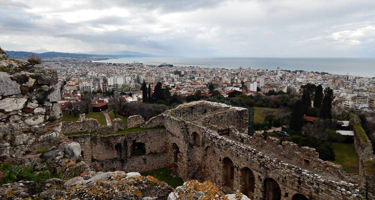 Des arches intérieures patinées d'un château perché encadrent la ville et le littoral en contrebas.