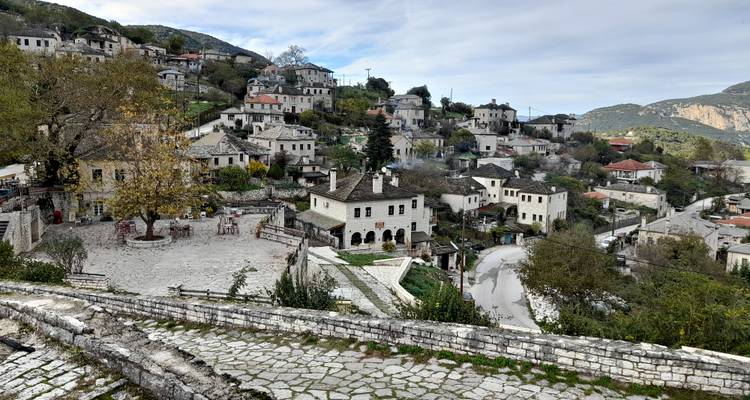 Pueblo tradicional de piedra con techos de pizarra que se extiende en cascada por una ladera rodeada de montañas.