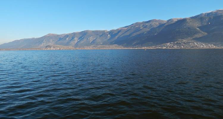 Un lac bleu profond s'étend devant une chaîne de montagnes sous un ciel dégagé.
