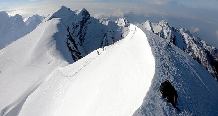 Groupe de grimpeurs marchant le long d'une crête de montagne enneigée.