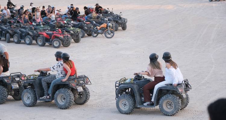 Grupo de personas montando vehículos todo terreno en un paisaje desértico.