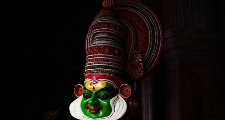 Masque de danse Kathakali coloré présenté sur un fond sombre.