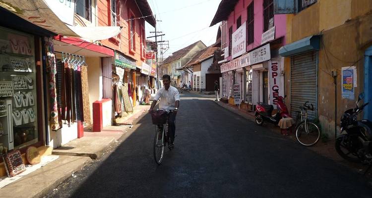 Un cycliste circulant dans une rue étroite bordée de bâtiments coloniaux colorés et de boutiques d'épices.