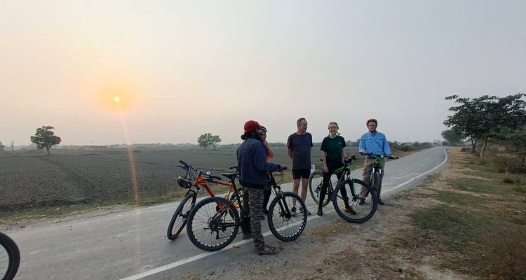 Grupo de ciclistas conversando en una carretera rural al atardecer.